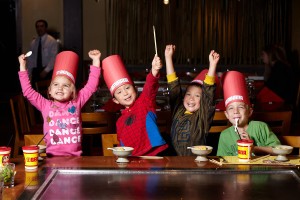 a group of kids wearing buckets and holding up their hands